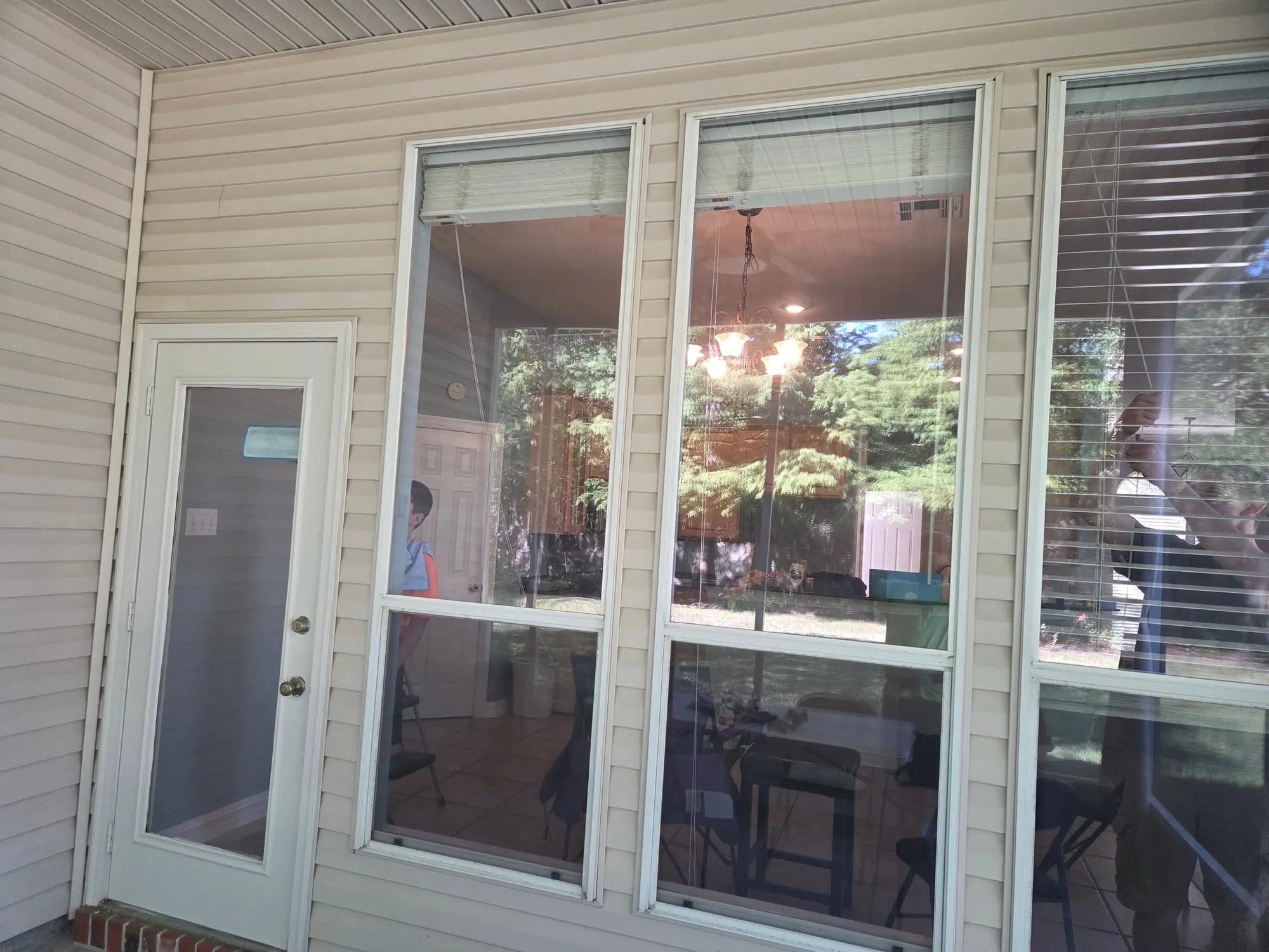 Tall clean windows beside a back door under a covered patio, looking into a bright kitchen